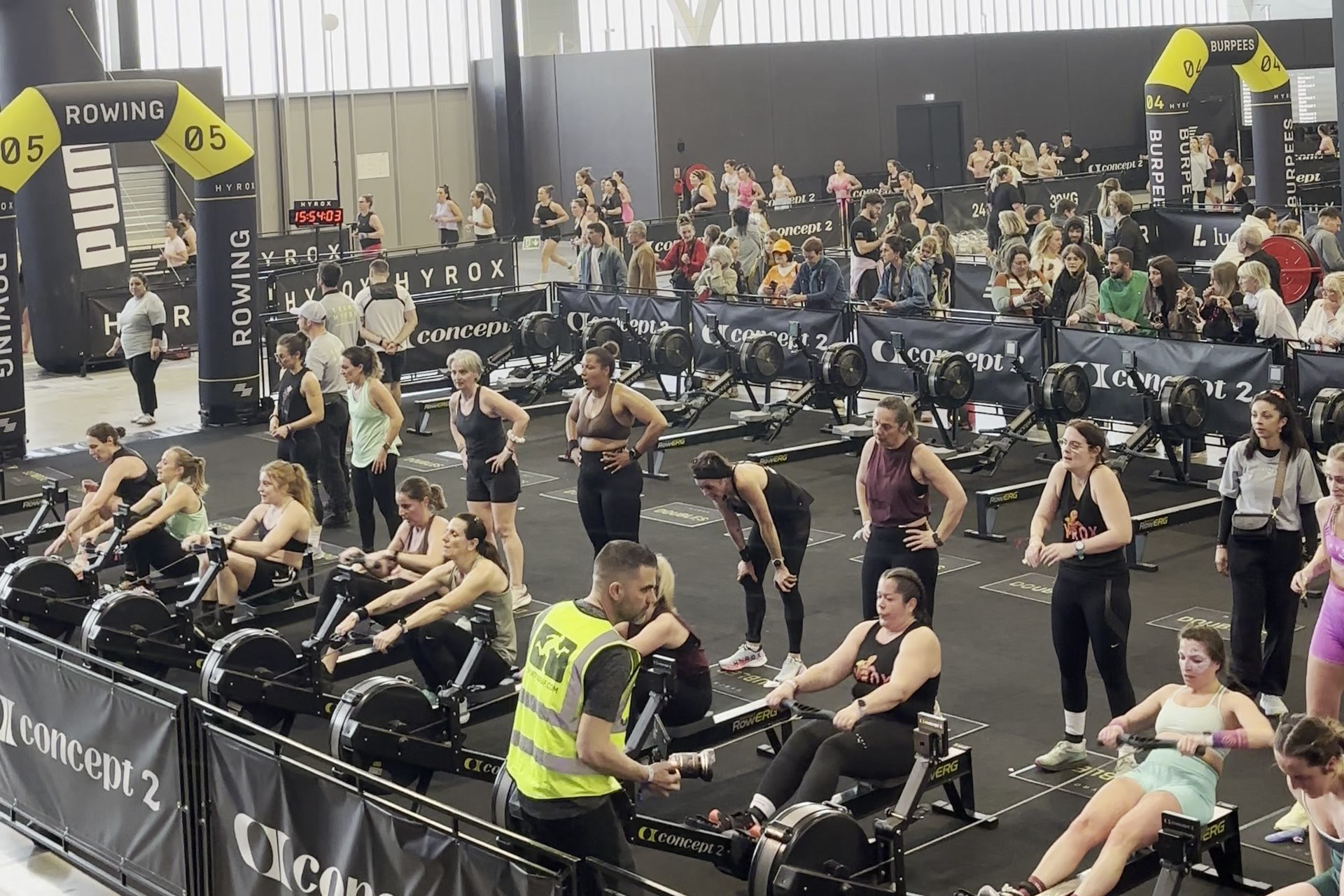 Rowing is the fifth station, with a judge on the floor and spectators behind the barriers.