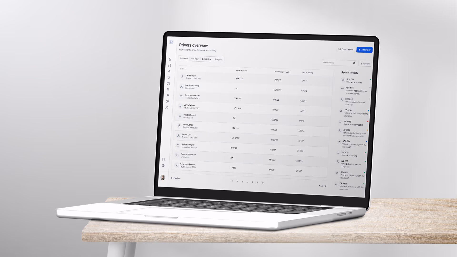 Laptop on a wooden table displaying a driver overview dashboard with names, vehicle details, license expiry dates, and recent activity.