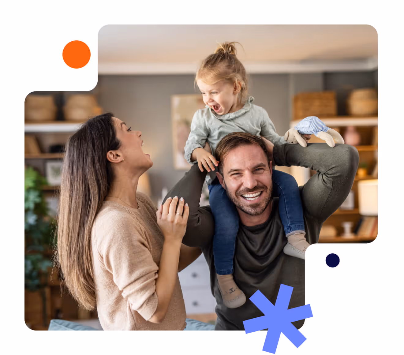 Smiling man carrying a laughing toddler on his shoulders with a happy woman beside them in a cozy living room.