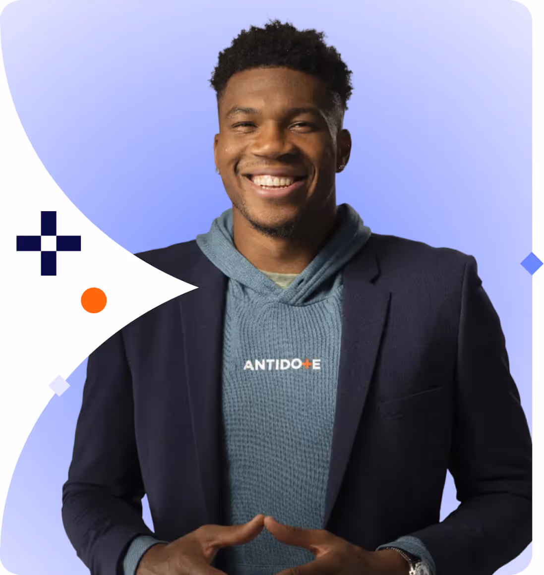 Smiling young man wearing a navy blazer over a blue hoodie with the word ANTIDOTE on it, standing against a blue and white abstract background.