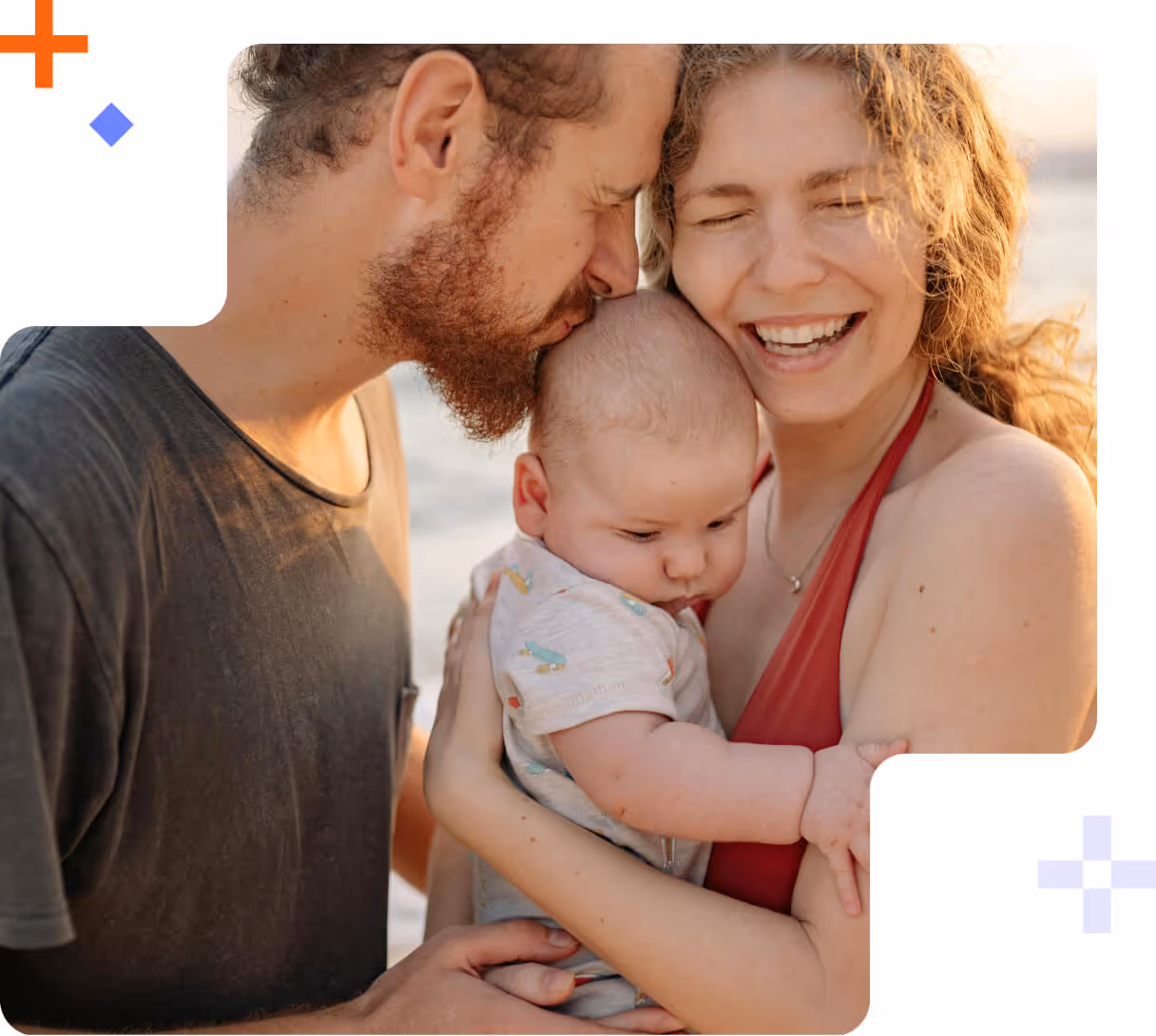 Man kissing baby’s head while woman smiles holding the baby outdoors.