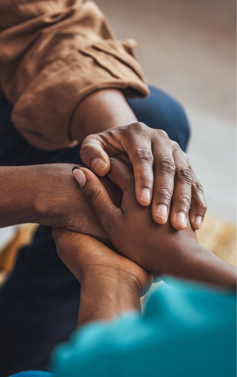 Close-up of two people holding hands in a comforting gesture.