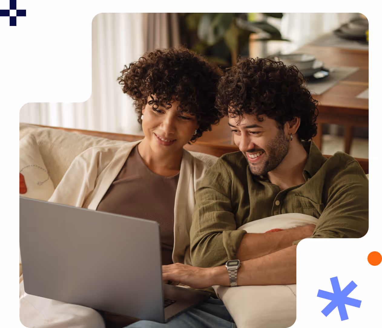 Smiling young couple sitting on a couch looking at a laptop screen together.