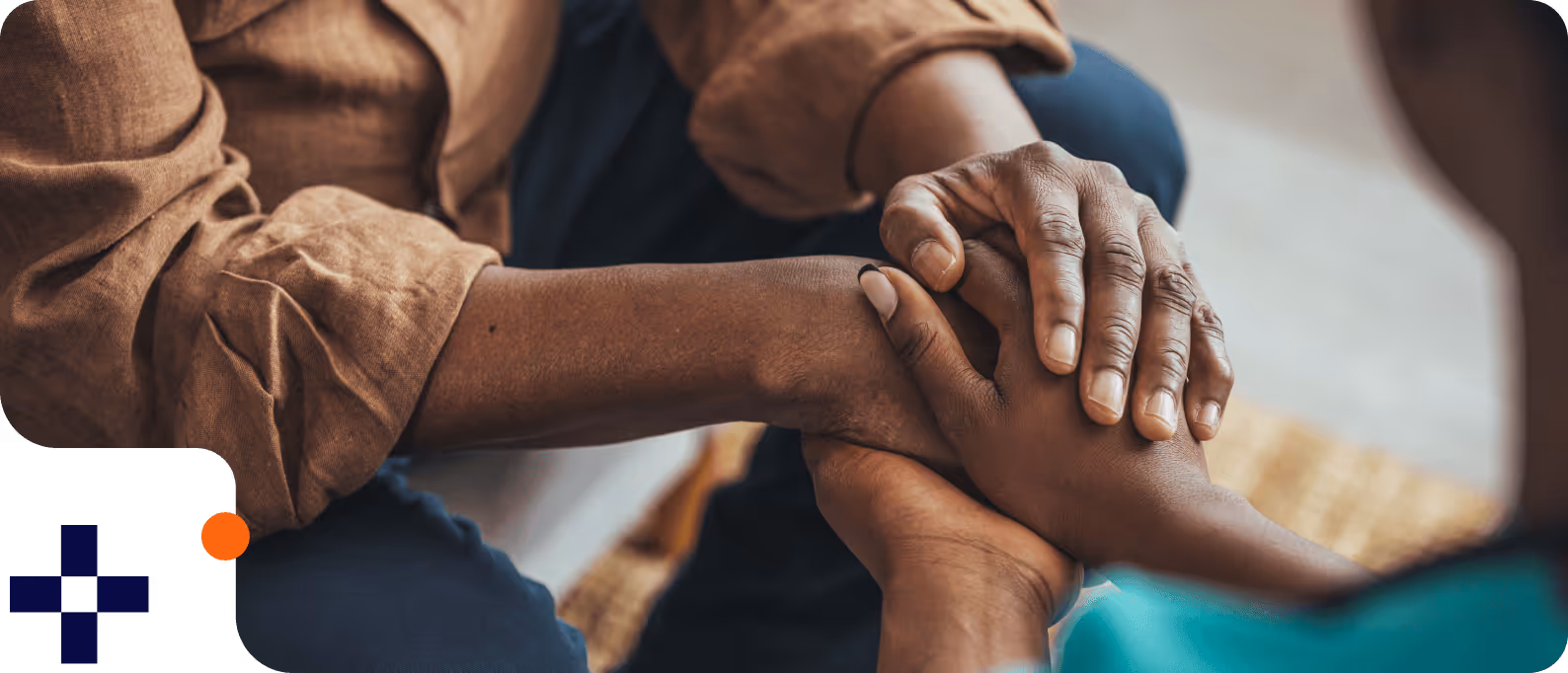Close-up of two people holding hands in a comforting gesture.