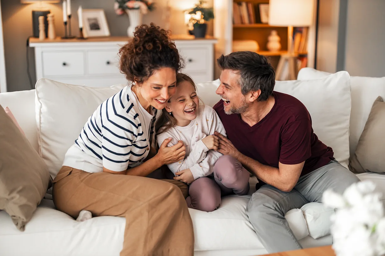 A family laughing together on the couch at home.