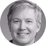 Smiling elderly woman with short white hair wearing a light-colored top.