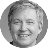 Smiling elderly woman with short white hair wearing a light-colored top.