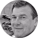 Smiling middle-aged man with short dark hair in black and white portrait.