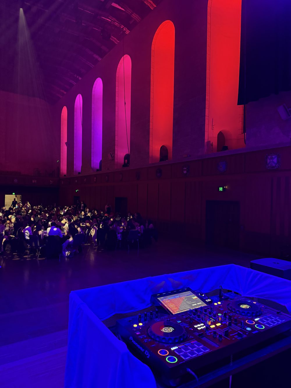Guests seated for dinner at a university ball in Winthrop Hall, UWA, with the Certified Entertainment DJ booth in the foreground