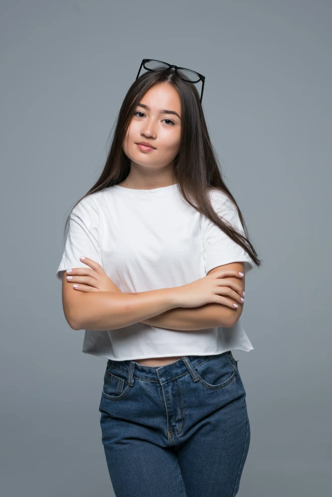 Portrait of woman in white top standing with crossed arms.