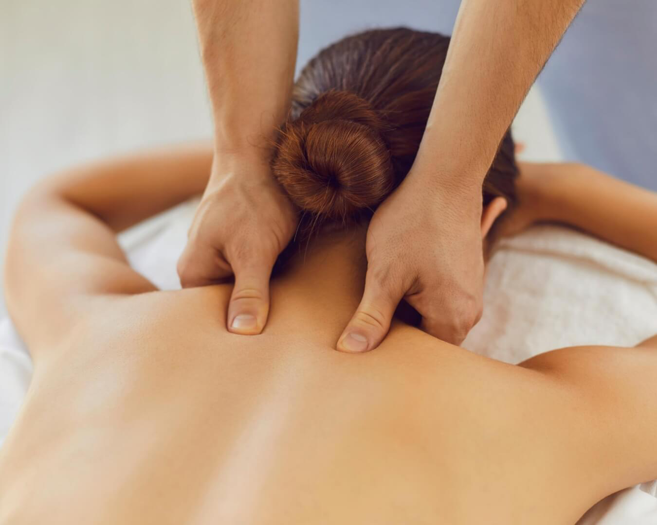 Person receiving a shoulder massage with hands applying pressure on the upper back.