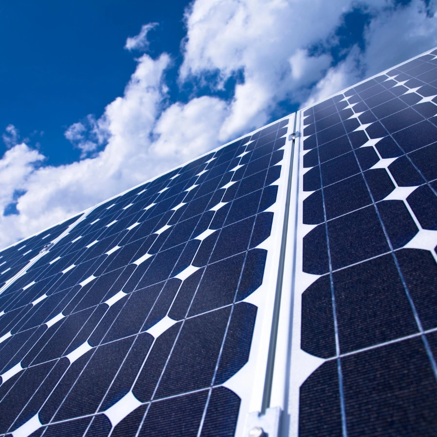 Paneles solares fotovoltaicos bajo un cielo azul con nubes blancas.