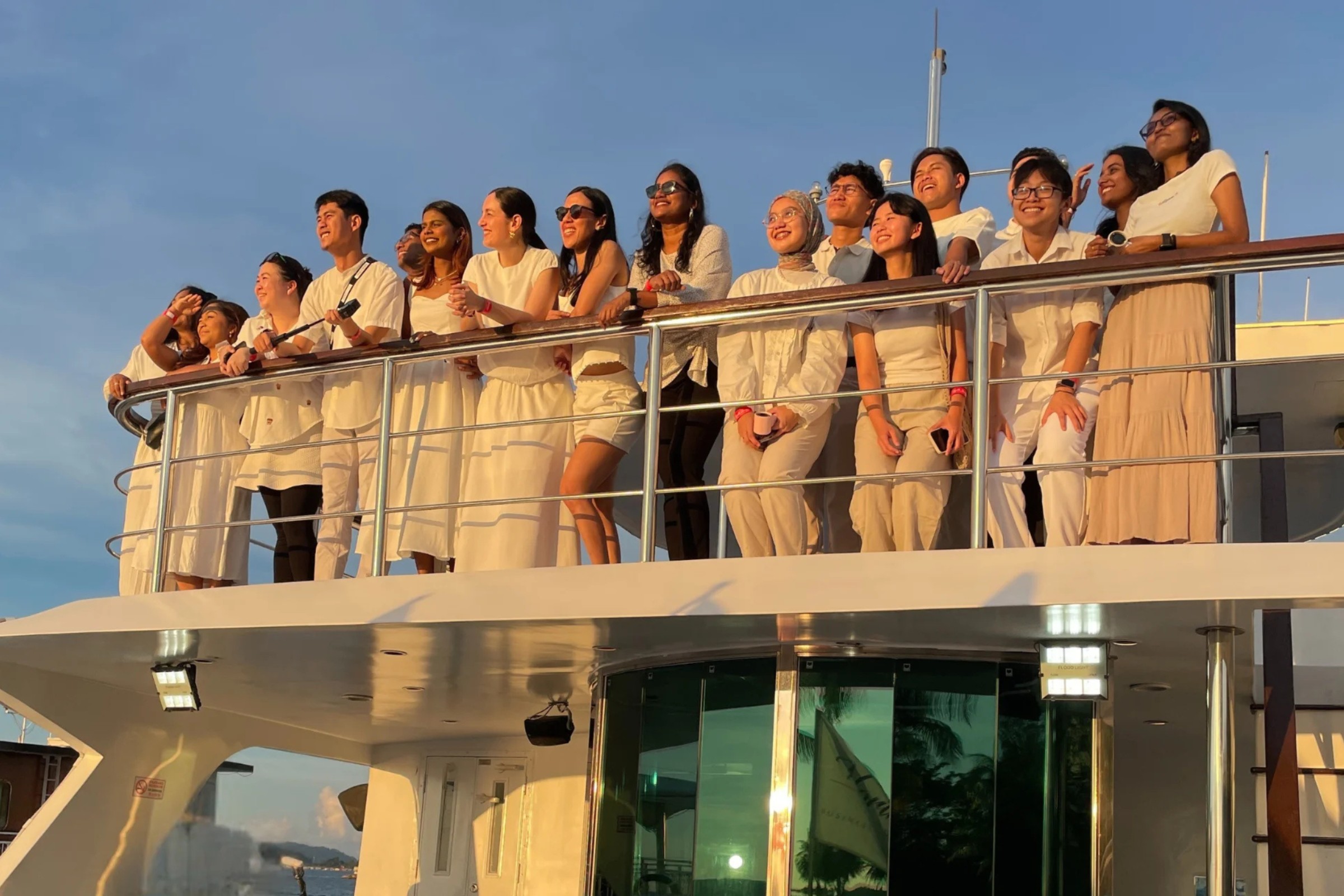 Group of people smiling and enjoying sunset on a deck.