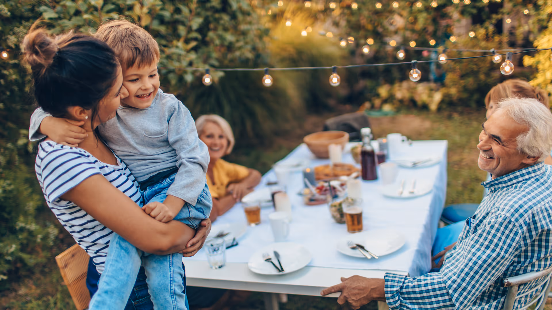 Photo of a multi-generation family having dinner outdoors in their back yard
