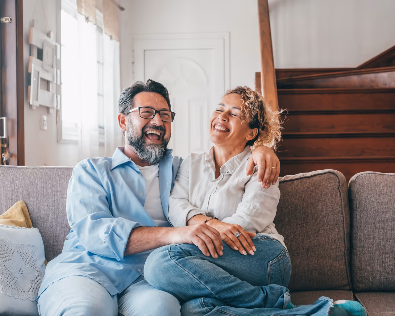 Happy caucasian couple laughing while sitting on sofa in the living room