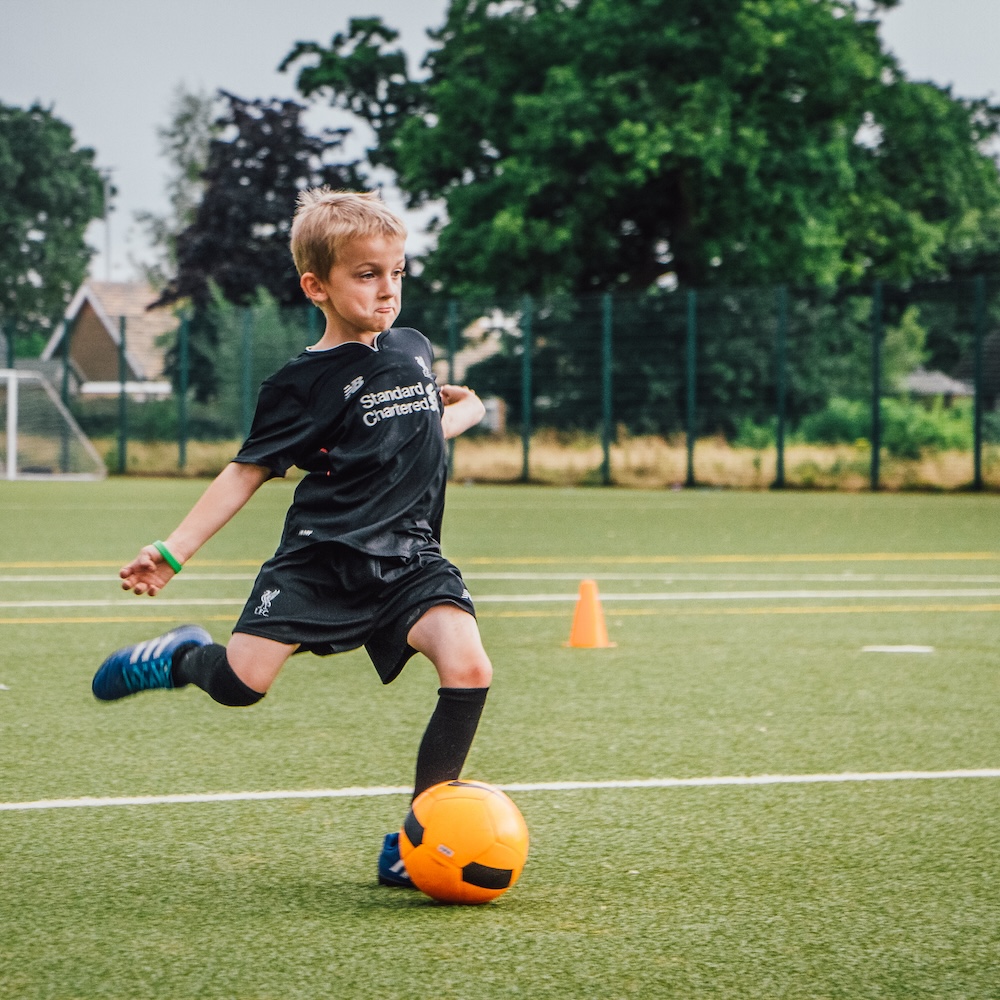 Child kicking a football in outdoor professional football court