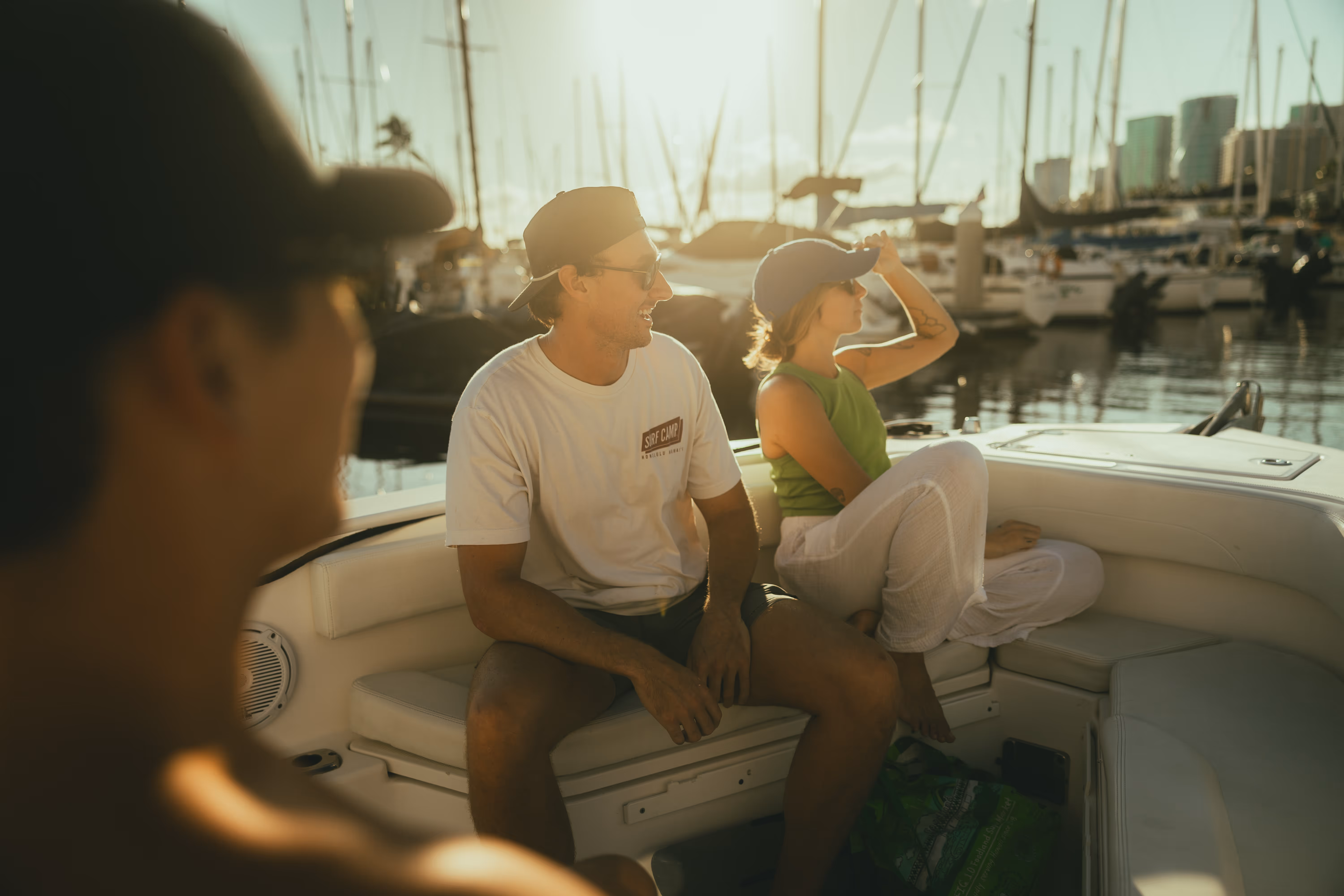 A small group lounging on Hawaii Apex Charters boat front seating, leaving the harbor for a sunset tour.