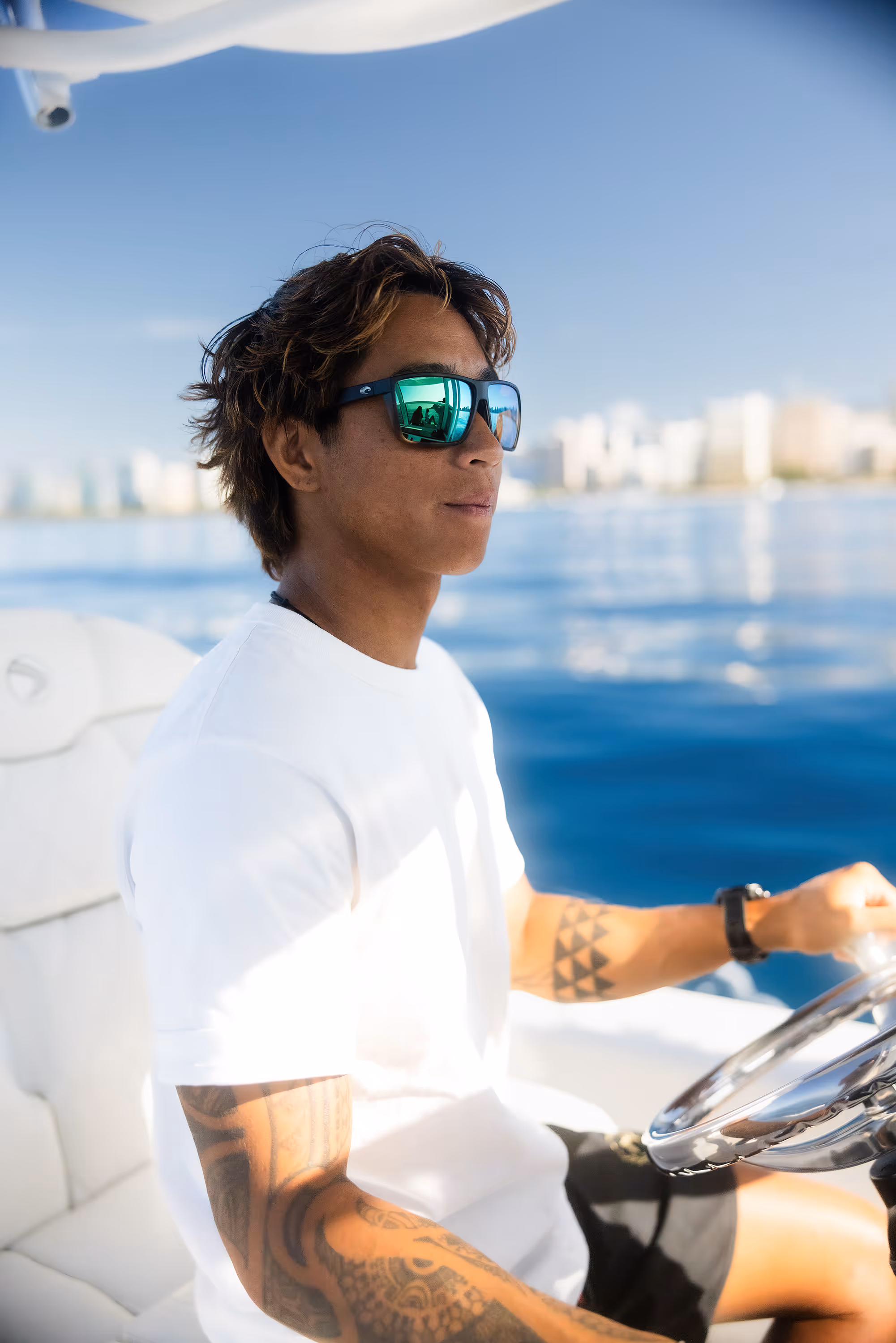 Hawaii Apex Charters founder Phillip Vu, at the wheel of his vessel, Kalihi, with the Waikiki skyline in the background.