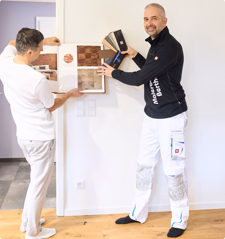 Zwei Männer vergleichen verschiedene Holzmuster in einem hellen Raum mit Holzboden.