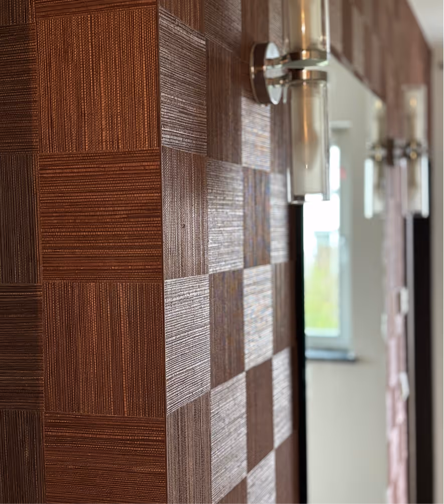 Nahaufnahme einer Wand verkleidet mit braunen, texturierten quadratischen Fliesen und modernen Wandlampen.