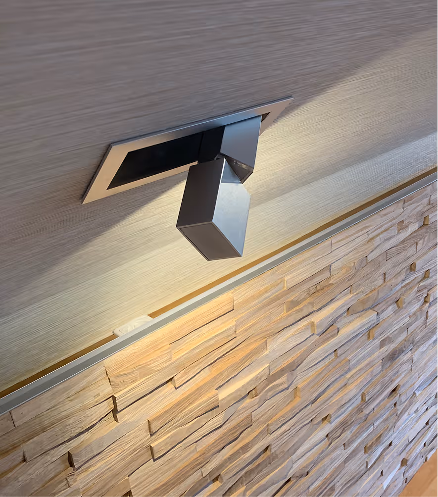 Moderne rechteckige Deckenleuchte aus Metall, die an einer hellen Holzwand mit 3D-Holzverkleidung montiert ist.