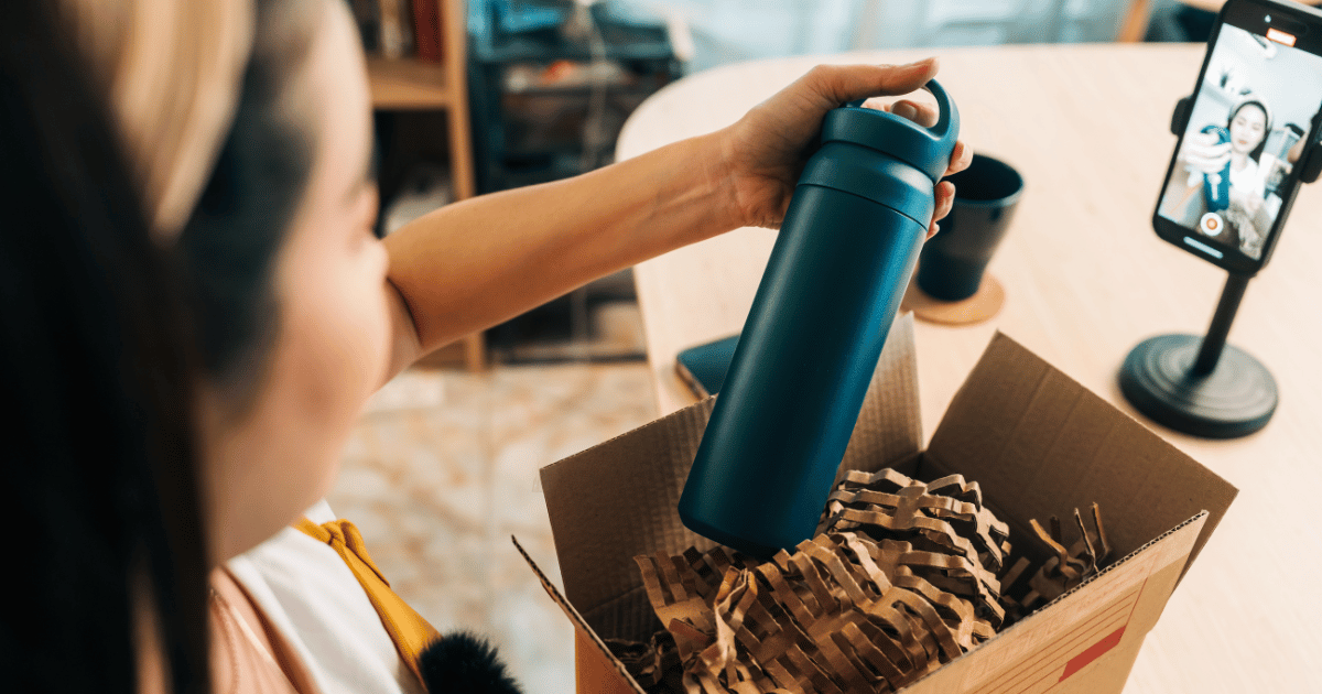 Young woman unboxing eco-friendly bottle during live stream