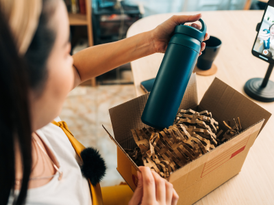 Young woman unboxing eco-friendly bottle during live stream