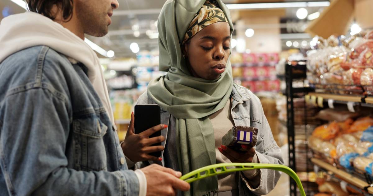 participant recording a video on their smartphone while examining a product label in a supermarket aisle