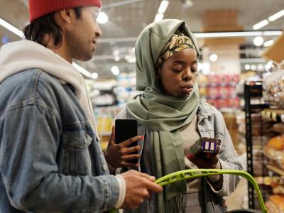 participant recording a video on their smartphone while examining a product label in a supermarket aisle