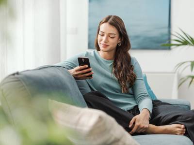 Lady using phone at home on sofa.
