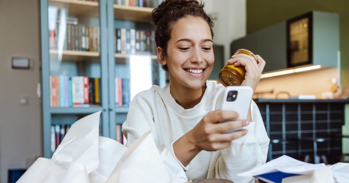 Women unpacking online ordered items and using smart phone