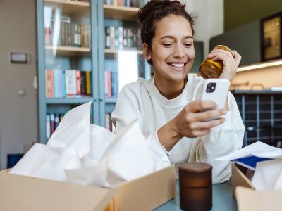 Women unpacking online ordered items and using smart phone
