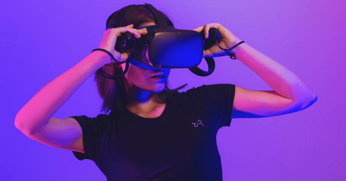Young female using VR headset with neon purple background.