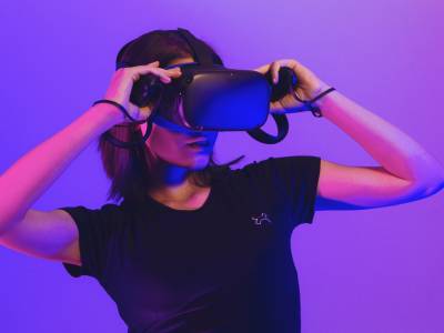 Young female using VR headset with neon purple background.