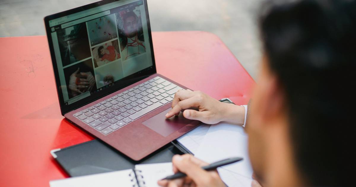 Laptop and Notebooks on Red Table.