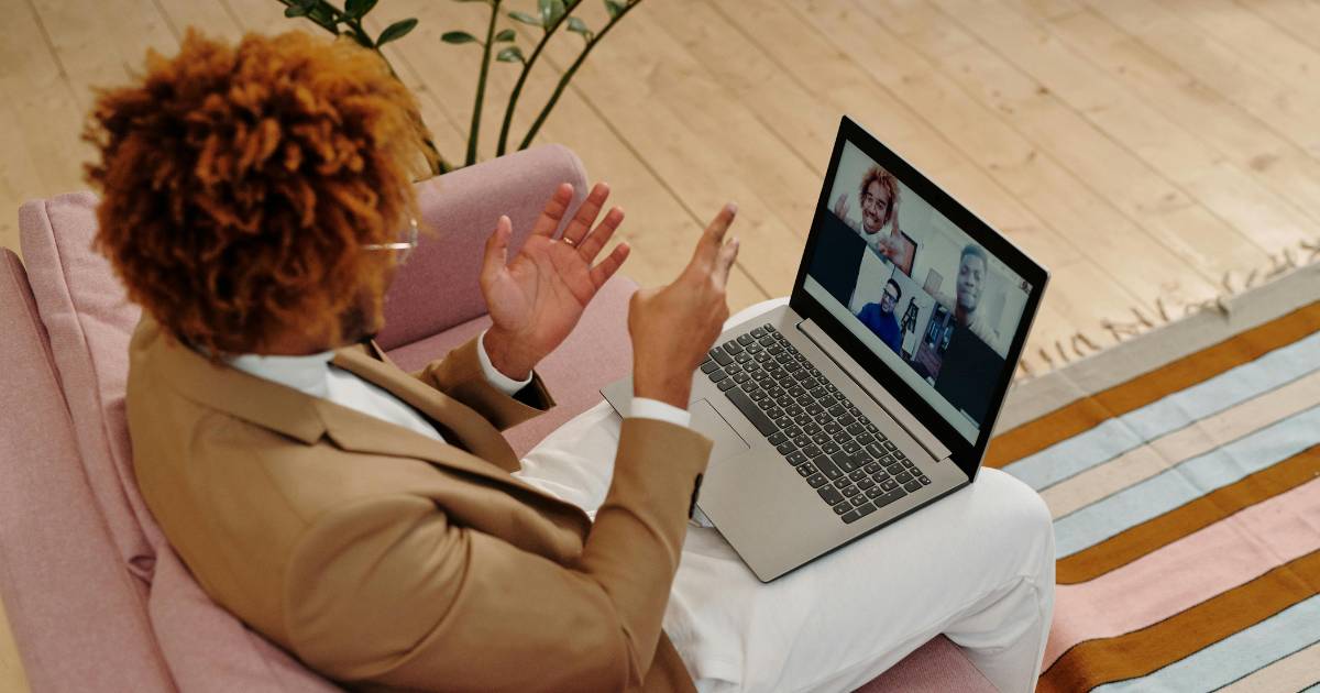 Man Sitting on Sofa Talking on Webcam on Laptop