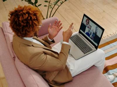 Man Sitting on Sofa Talking on Webcam on Laptop
