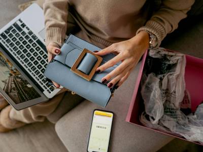 Woman Sitting on a Couch with a Laptop on Her Lap and Holding a New Purchase.