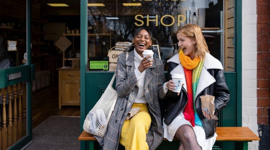 Friends having coffee outside shop.