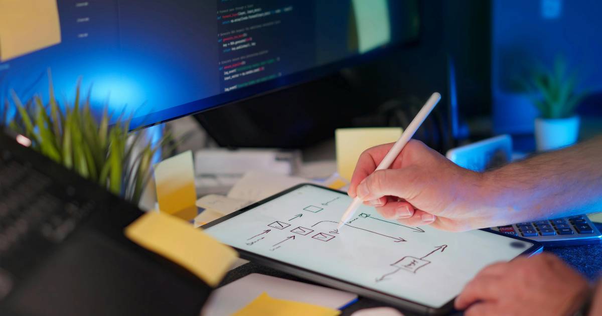Hands Writing Notes for Coding Project at Desk.