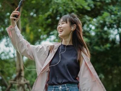 Happy woman with smartphone and earphones.