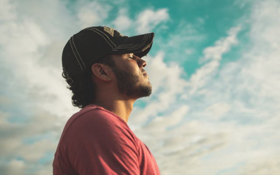 Man looking out into distance with blue sky behind him.