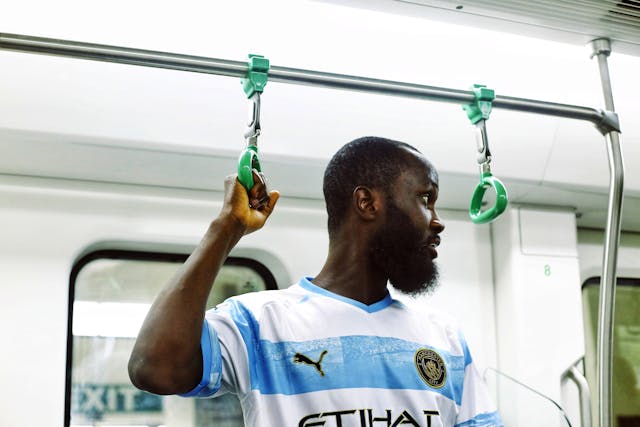 Manchester city fan on a train, travelling to game in their jersey/ 
