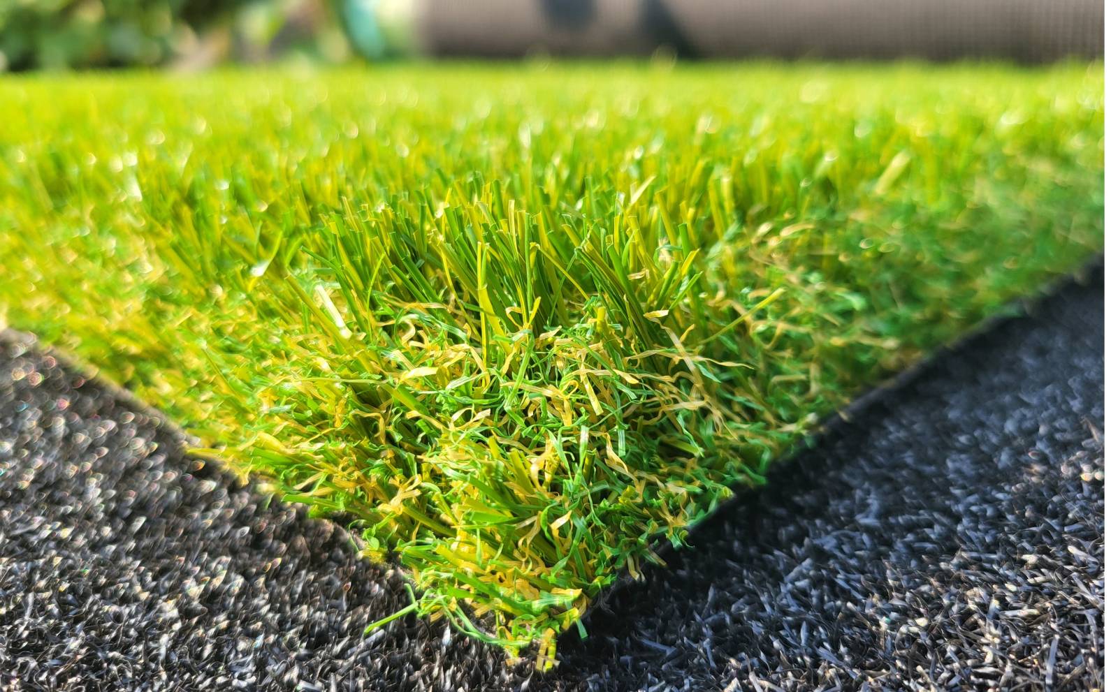 Gros plan sur une pièce de gazon artificiel vert posée sur une surface noire texturée.
