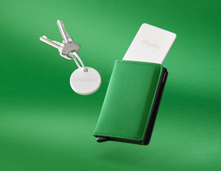 Green Secrid wallet with a white Chipolo tracker partially inserted and a set of keys attached to a round Chipolo tracker on a green background.