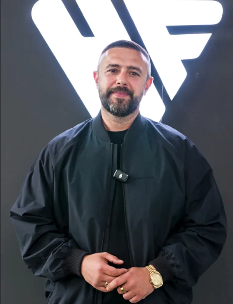 Mann mit kurzem Bart und schwarzen Jacke vor weißem Headfound Logo auf dunklem Hintergrund.