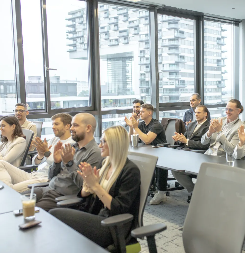 Eine Gruppe von Mitarbeitern sitzt in einem modernen Büro und klatscht.