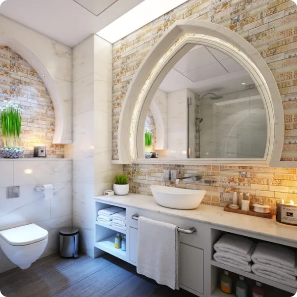 Modern bathroom with arched mirror illuminated by LED lights, white vessel sink on marble countertop, and stacked towels below.