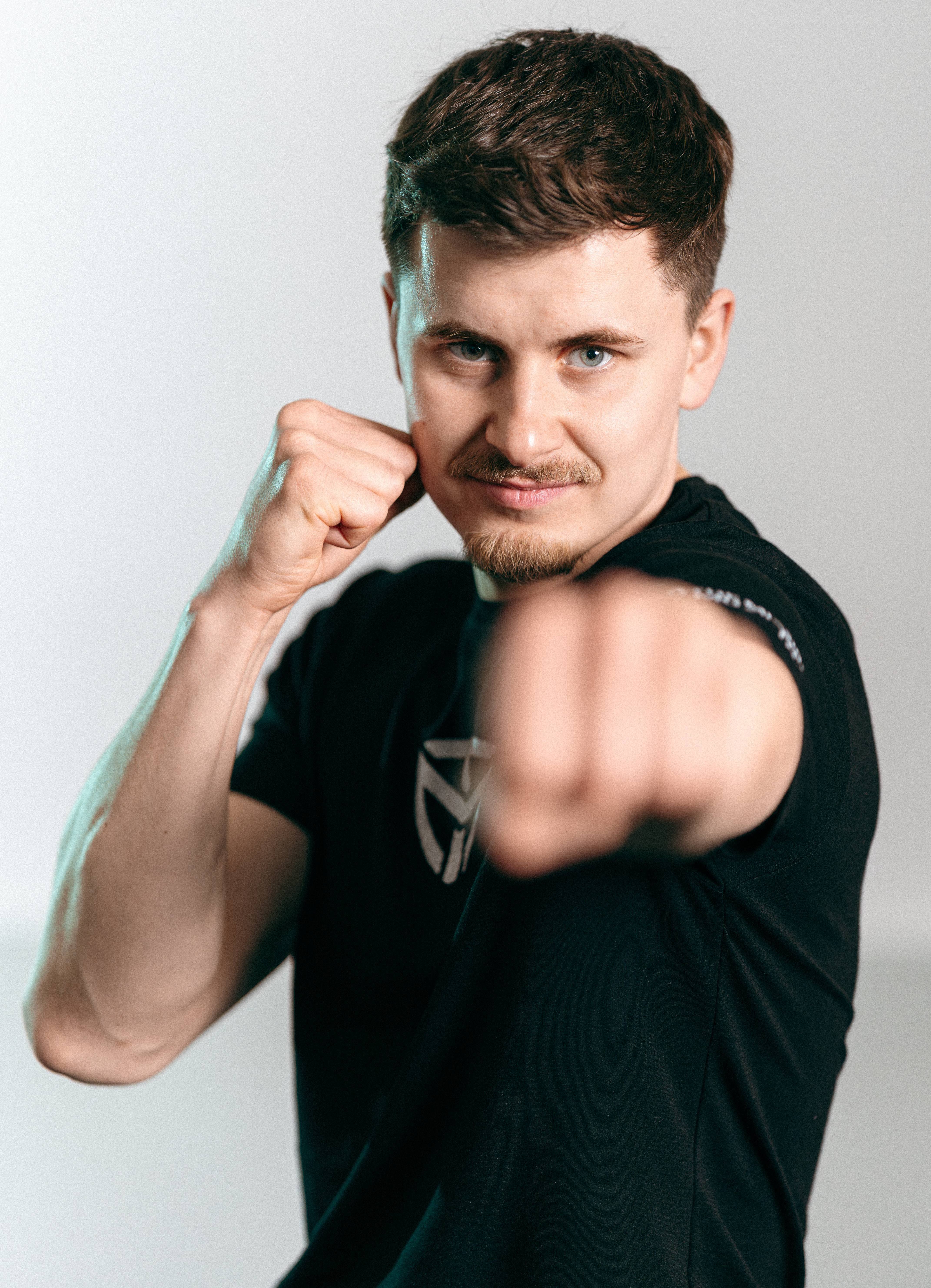 Man in black shirt throwing a punch toward the camera with focused expression.