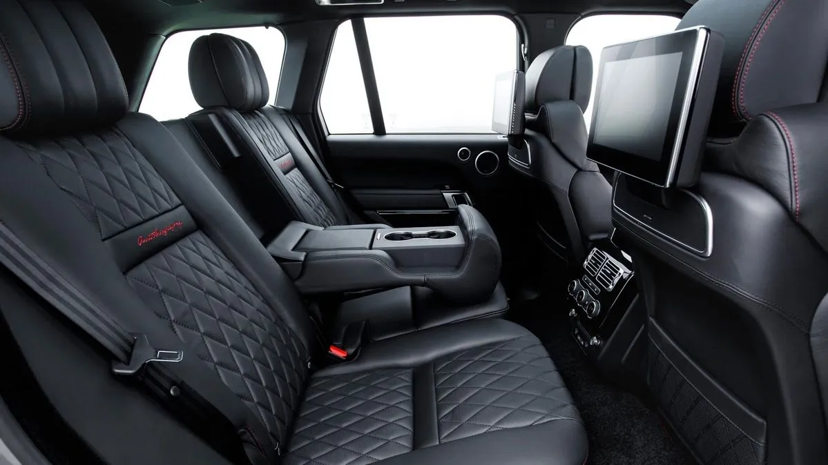 Rear interior of a luxury black leather SUV with quilted seats and built-in rear seat entertainment screens.